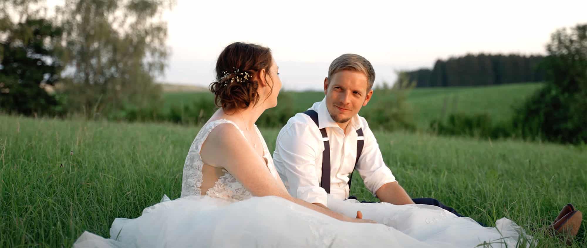 Brautpaar sitzt am Hügel beim Sonnenuntergang